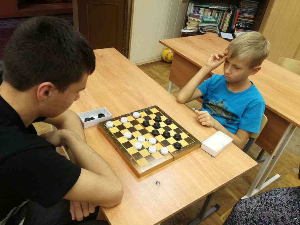 Игра игроками с шашкой. Турнир по шашкам. Шашки школьники. Люди играющие в шашки. Дети играют в шашки.